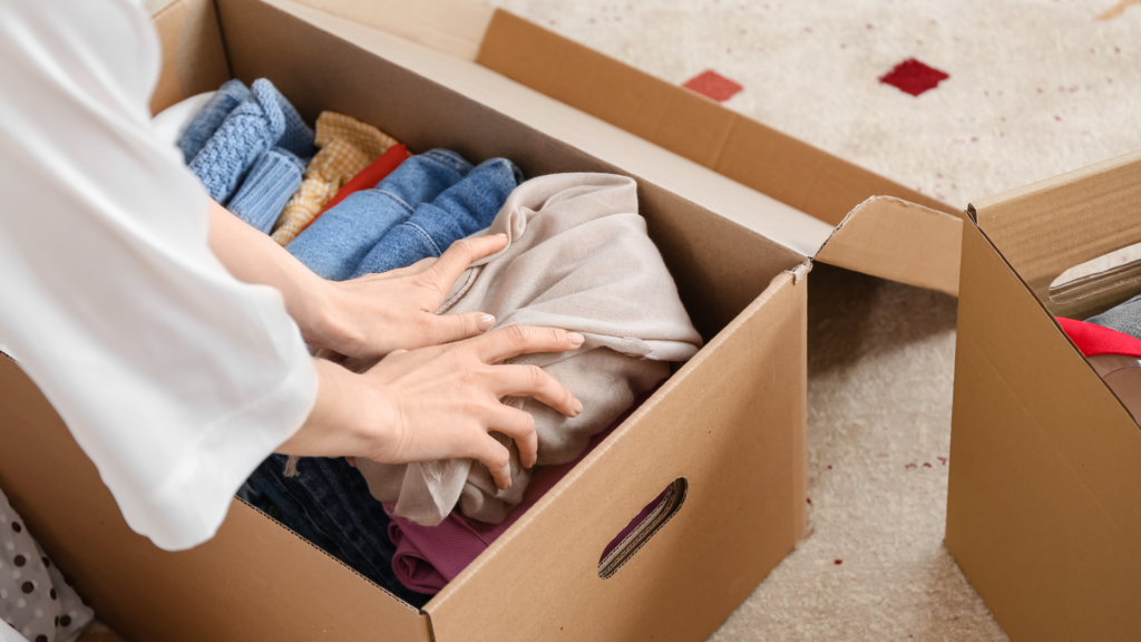 femme qui met des vêtements dans un carton